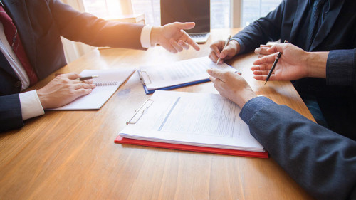 business people and lawyers discussing contract papers sitting a