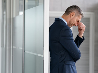 Stressed businessman suffering headache in office