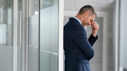 Stressed businessman suffering headache in office