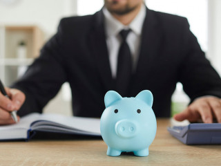 Piggy bank on desk of accountant who uses calculator to analyze budget and make calculations.