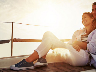 Hug, sunset and couple on a yacht for travel, retirement holiday and ocean adventure in Spain. Investment, hobby and man and woman on a boat for a luxury cruise, sailing and happiness at sea