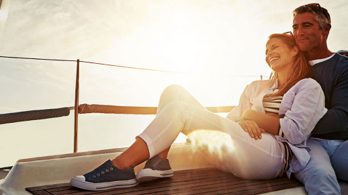 Hug, sunset and couple on a yacht for travel, retirement holiday and ocean adventure in Spain. Investment, hobby and man and woman on a boat for a luxury cruise, sailing and happiness at sea