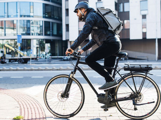 Male courier with bicycle delivering packages in city. Copy space.