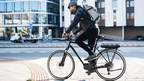 Male courier with bicycle delivering packages in city. Copy space.