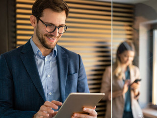 Happy professional successful business man using tablet and working in office