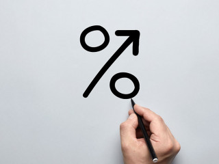 Male hand drawing a big percent sign on gray background with a p