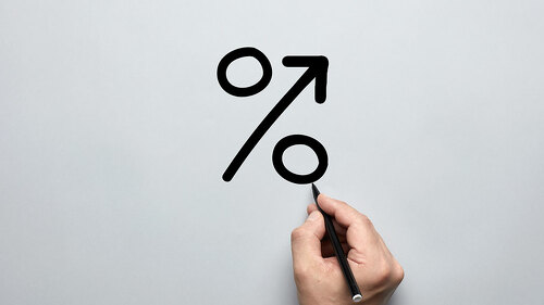Male hand drawing a big percent sign on gray background with a p