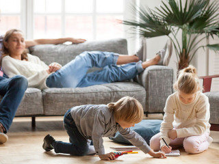 Children siblings playing drawing together while parents relaxin