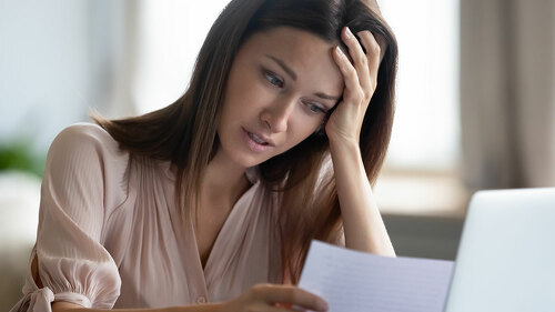 Unhappy woman holding paper, reading bad news in letter