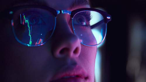 Close up view of girl's eyes in glasses looking at pc screen with computer reflection at eyewear. Using internet, working online. Technology, AI, business