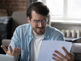 Annoyed frustrated entrepreneur looking at paper report with bad news