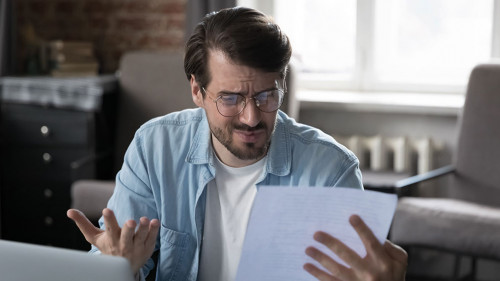 Annoyed frustrated entrepreneur looking at paper report with bad news
