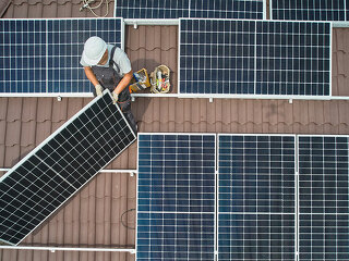 Men technicians mounting photovoltaic solar moduls on roof of house.