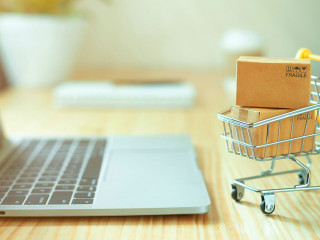 Brown paper boxs in a shopping cart with laptop keyboard on wood