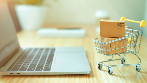 Brown paper boxs in a shopping cart with laptop keyboard on wood