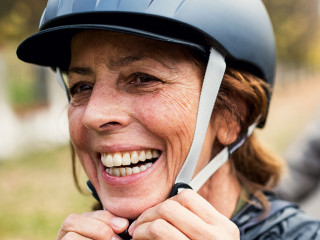 Active senior couple with electrobikes standing outdoors on a road in nature.