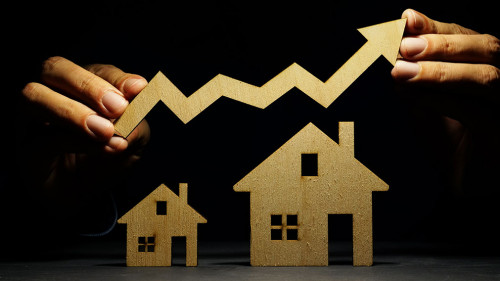 Property investment. Models of house and hand holding arrow.