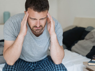 Restless man waking up early with headache after rough night
