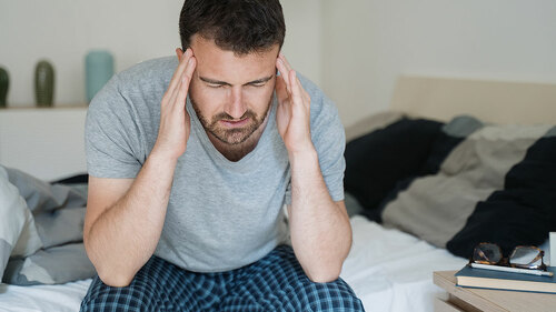 Restless man waking up early with headache after rough night