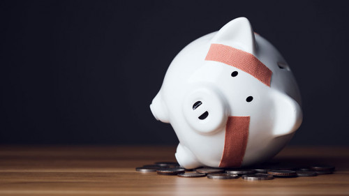 Financial problem, Bankrupt or fail in business concept. White piggy bank with plastic adhesive bandages on wooden desk with dark copy space wall background. Fail, Bankrupt or unsuccessful idea.