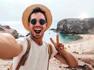 Handsome man wearing hat and sunglasses taking selfie picture on