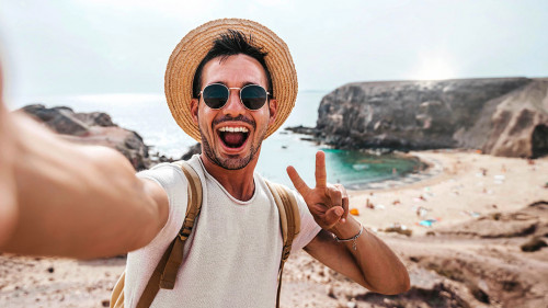 Handsome man wearing hat and sunglasses taking selfie picture on