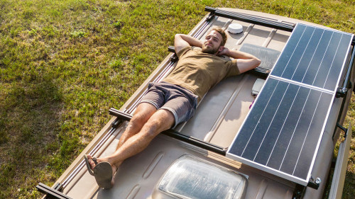 Man relaxing on the roof of a camper van