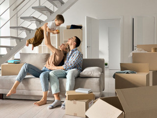 Happy young family playing with kid son together in new home on moving day.