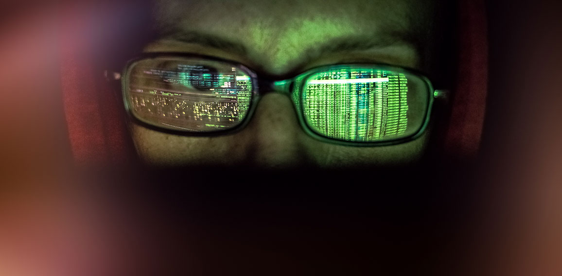 hacker at computer data reflecting in eyeglasses