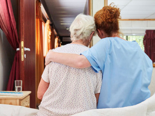 Krankenpflegerin umarmt Seniorin in Hospiz zum Trösten