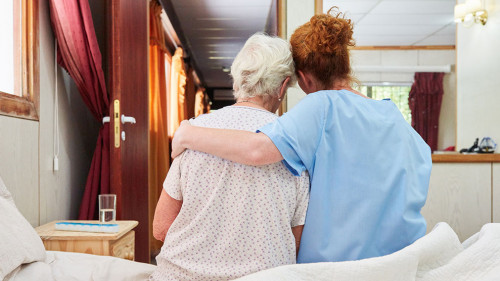 Krankenpflegerin umarmt Seniorin in Hospiz zum Trösten