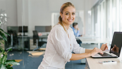 Business woman working on laptop in office while sitting on pila