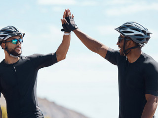 High five, winner and cycling team of cyclists having fun riding together outdoors in nature. Happy, excited and fit male bicycle riders on a break after exercising and training in the environment