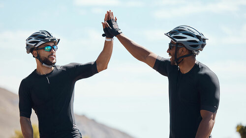 High five, winner and cycling team of cyclists having fun riding together outdoors in nature. Happy, excited and fit male bicycle riders on a break after exercising and training in the environment