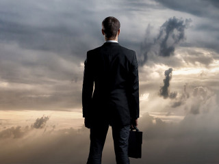 Businessman with briefcase standing over dark, dramatic ocean ba