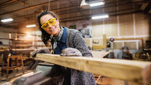 Professional carpenter woman choosing and preparing wood at stee