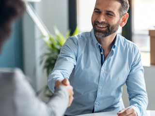 Attractive real-estate agent shaking hands with young couple aft