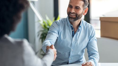 Attractive real-estate agent shaking hands with young couple aft