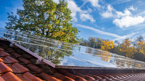 Wet photovoltaic modules in front of blue and cloudy autumn sky