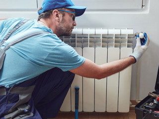 Central heating mechanic and handyman fixing home radiator, gas