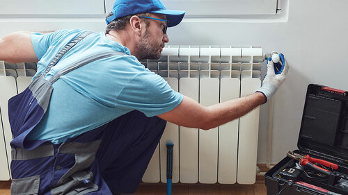 Central heating mechanic and handyman fixing home radiator, gas