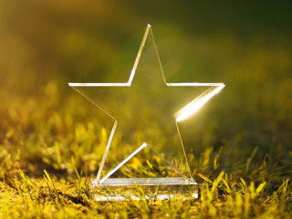 Transparent five-pointed star made of glass on a green summer ba