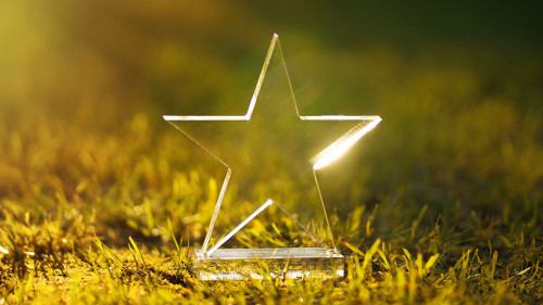 Transparent five-pointed star made of glass on a green summer ba