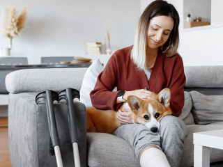 Adult woman in her late twenties on couch at home with crutches