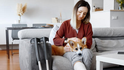 Adult woman in her late twenties on couch at home with crutches