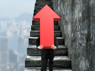 Businessman carrying red arrow sign climbing on stairs