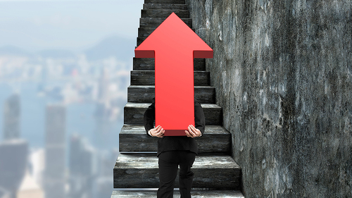 Businessman carrying red arrow sign climbing on stairs