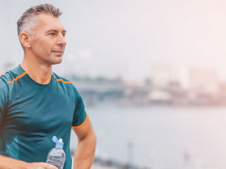 Portrait of healthy athletic middle aged man with fit body holdi