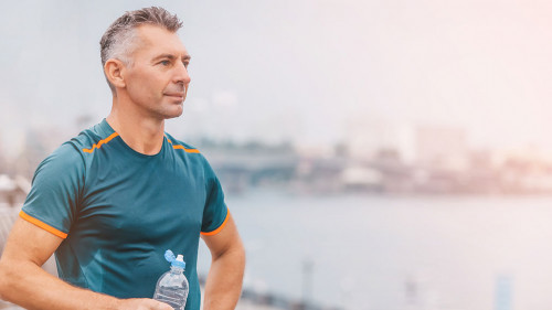 Portrait of healthy athletic middle aged man with fit body holdi