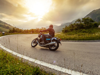 Motorcycle driver riding in Alpine landscape.